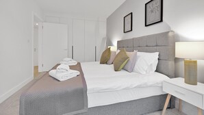 A modern hotel room with a large bed, a bedside table with a lamp, and a wardrobe. - Belmore 1 & 2 Bedroom Luxury Apartment (Stanmore)