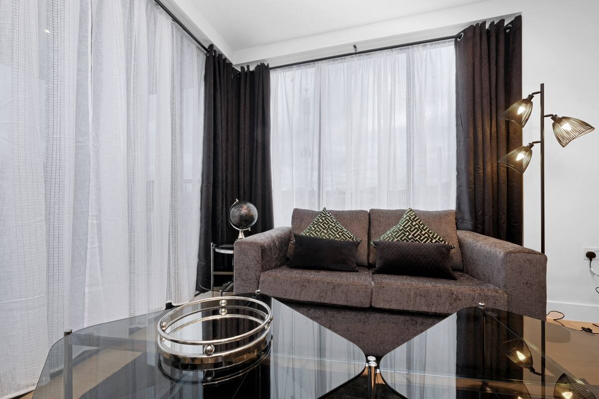 A modern living room with a sofa, a glass coffee table, and a lamp.