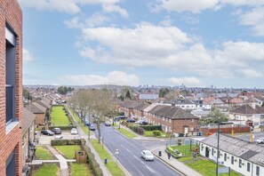 A residential street with houses, parked cars, and a clear sky.
