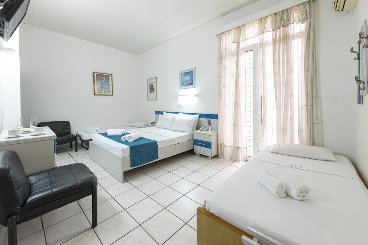 A hotel room with a bed, bedside table, chair, and a desk with a chair.