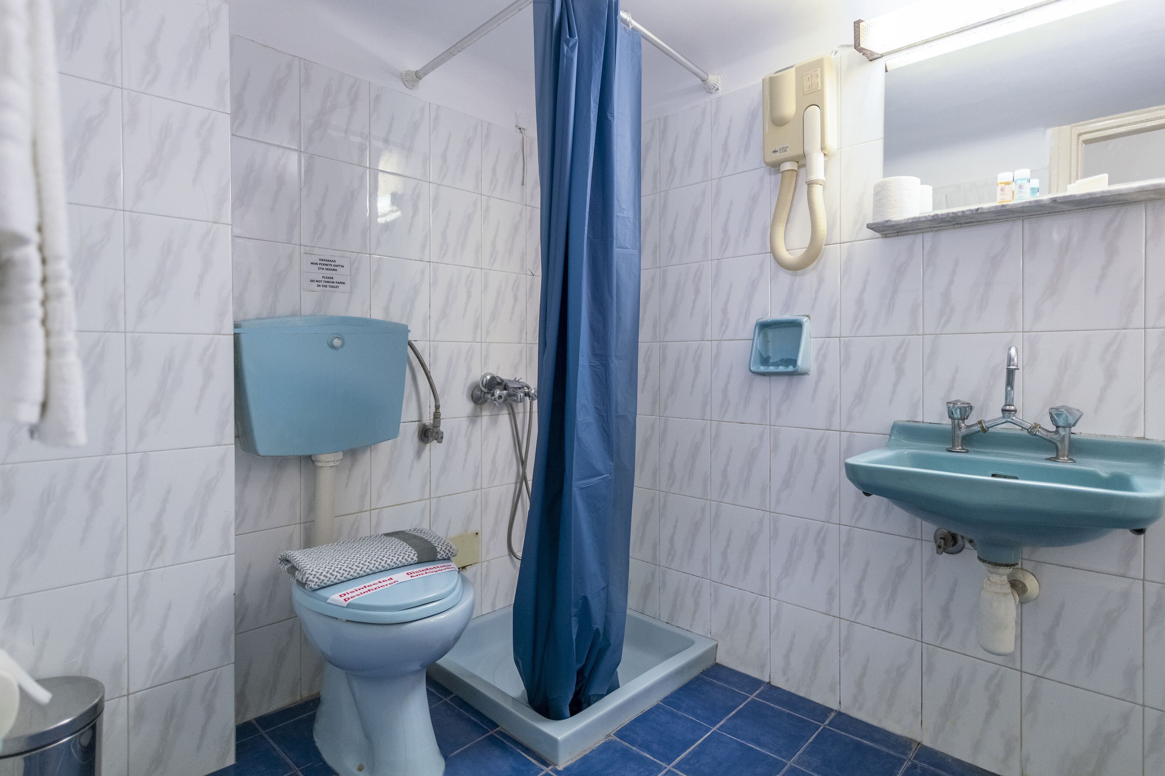 Une salle de bain équipée de toilettes, d’une douche, d’un lavabo et d’un sèche-mains.