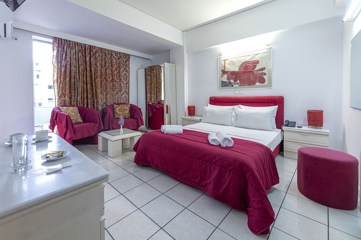 A hotel room with a bed, a desk, a chair, a mirror, and a window with curtains.