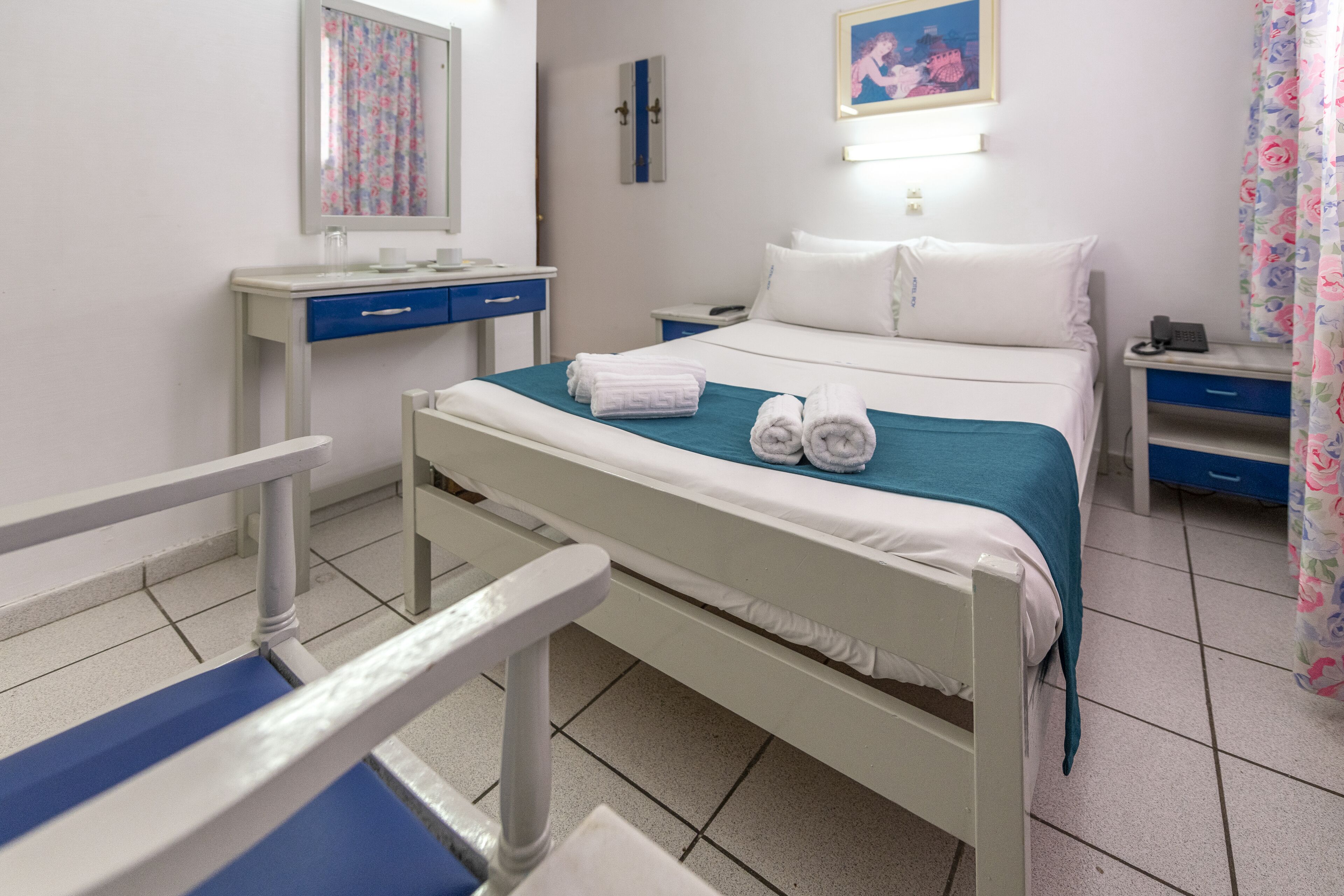 A hotel room with a bed, a desk, a chair, and a nightstand.