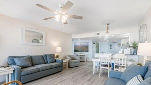 Ein Wohnzimmer mit grauem Sofa, Holzboden und Deckenventilator.
