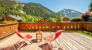 A wooden deck with two red chairs and a small table, surrounded by a wooden fence with Christmas tree decorations. - Terrace, tv, 130m², Champagny-en-Vanoise (Champagny-en-Vanoise)