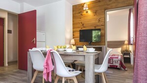 Ein zeitgemäßer Essbereich mit einer Holzwand, einem Flachbildfernseher und einem gemütlichen Bett mit einem gemusterten Überwurf.