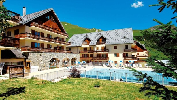 Ein mehrstöckiges Hotel mit Poolbereich, Steinwänden und Balkonen.