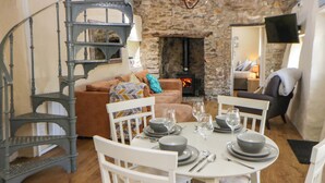 A dining area with a round table set for four, white chairs, and a spiral staircase in the background. - Cobwebs (Kilgetty)