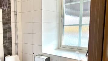 Ett badrum med toalett, handfat och ett fönster.