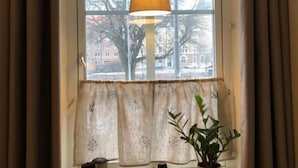 A cozy room with a window, a lamp, a kettle, a mug, and a potted plant. - Hotell Alderholmen (Gävle)