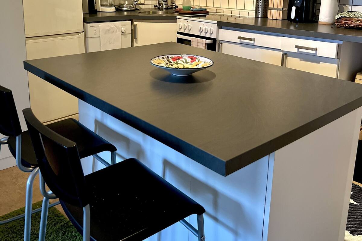 A modern kitchen with white cabinetry, a central island with a bowl, a coffee maker, and a microwave.