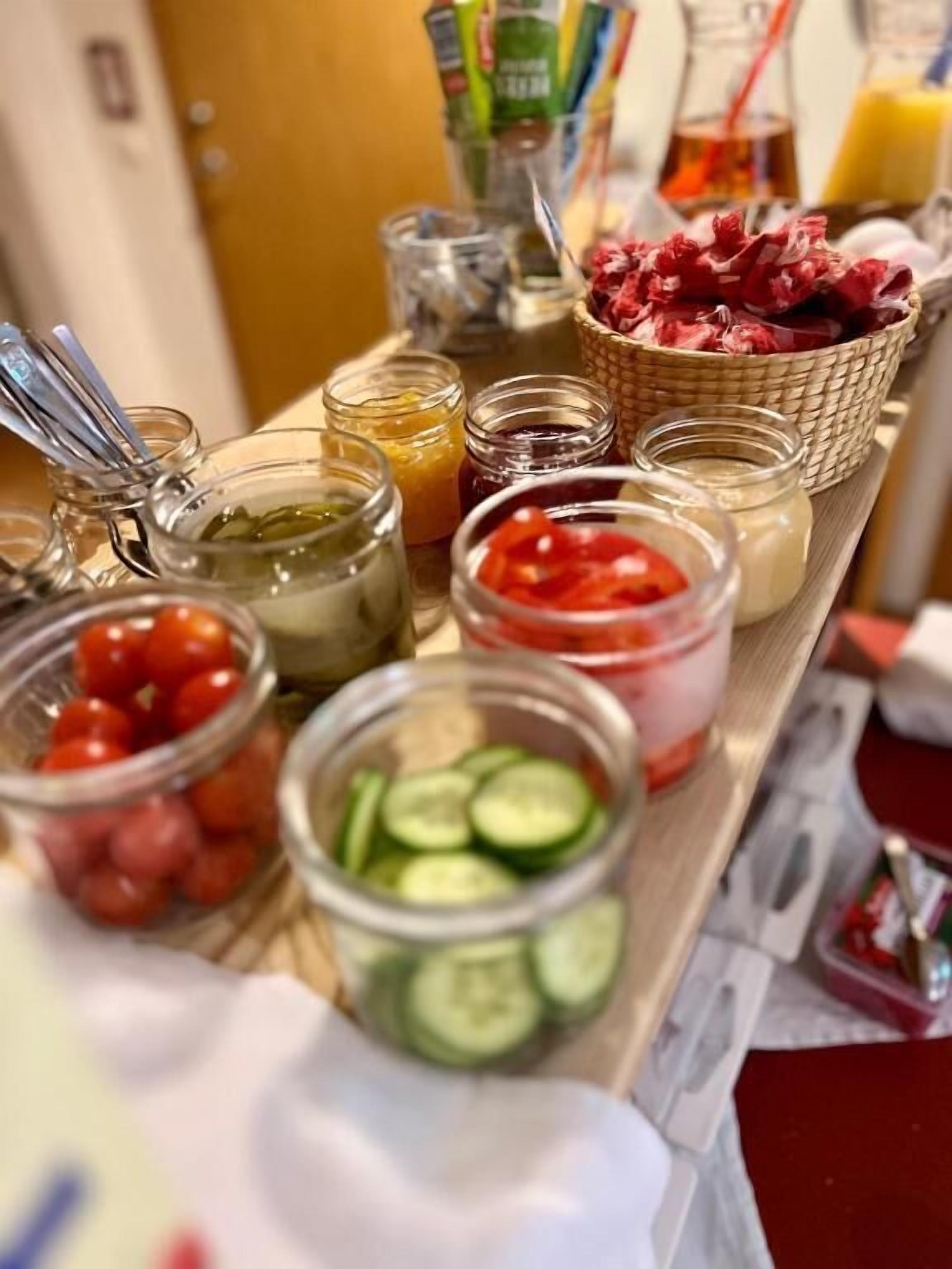 A buffet table with various food items including tomatoes, cucumbers, and pickled vegetables.