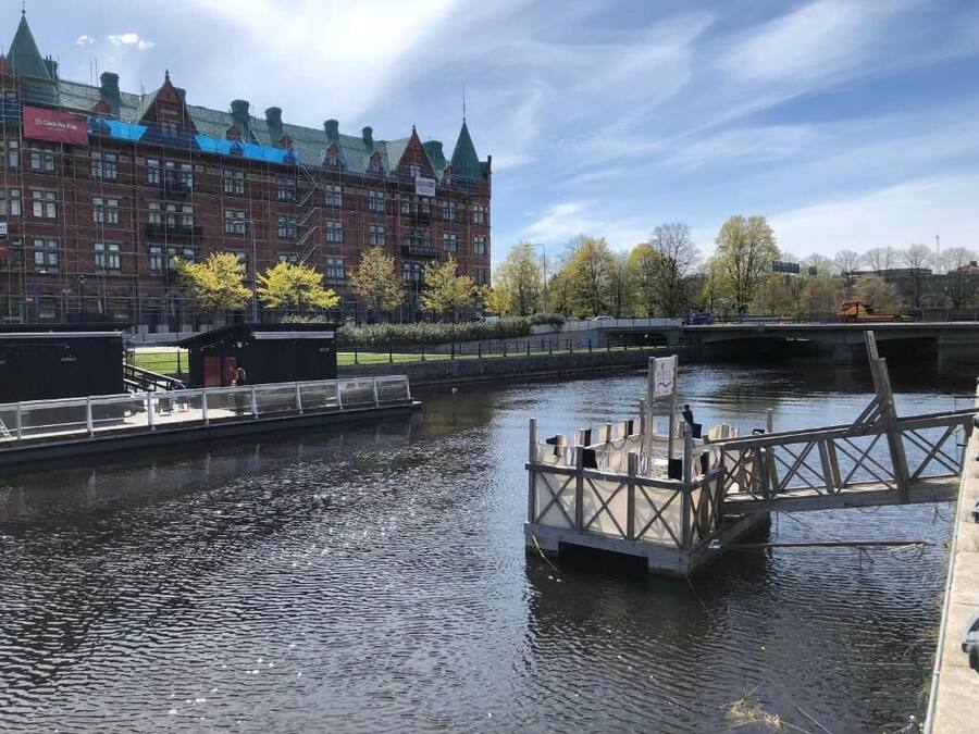 Un canal con un muelle de madera y un puente al fondo.