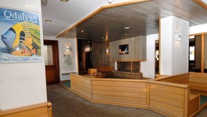 A hotel lobby with a wooden reception desk, a fireplace, and a poster advertising Odalys vacations. - 200m from resort center, balcony, tv, ski locker, 26-30m², Val d'Isère (Val-d'Isère)