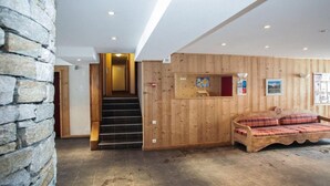 A hotel room with a stone wall, wooden paneling, a staircase, and a sofa. - 100m from ski slopes, tv, 30m², Tignes (Tignes)