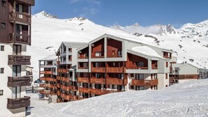 Et hotel med flere etager og balkoner, med et sneklædt bjerg i baggrunden.