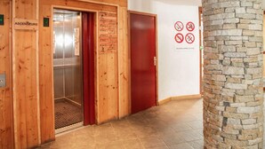 En træelevator med dør i rødt, et skilt med reception og en kampesten.