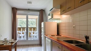 Uma cozinha com uma janela grande, armários de madeira, uma pia de aço inoxidável e micro-ondas embutido.