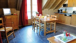 Una cocina acogedora con armarios de madera, una mesa de comedor con sillas, un televisor y una zona para el desayuno.