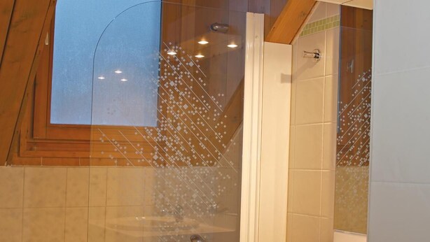 A bathroom with a skylight, a bathtub, and a vanity with a mirror.