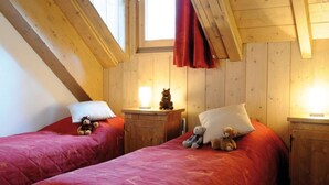 Una habitación acogedora con dos camas, paredes de madera y techo inclinado.