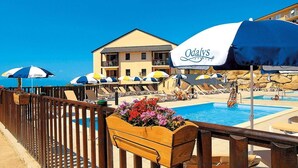 A poolside area with lounge chairs, umbrellas, and a wooden planter with flowers. - Wifi, swimming pool, terrace, balcony, parking, tv, ski locker, 22m², Font Romeu (Font-Romeu-Odeillo-Via)