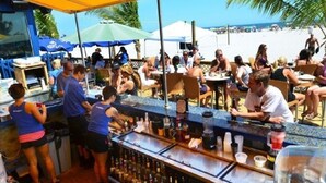 A bar area with a counter, stools, and a crowd of people. - Brigantine Beach - 1BR/1BA - Oceanfront property! (Brigantine)