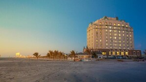 A large, multi-story hotel with a classic architectural style, located on a beach with palm trees and a clear sky. - Brigantine Beach - 1BR/1BA - Oceanfront property! (Brigantine)