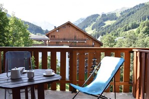 Eine Holzterrasse mit Tisch und Stühlen mit Blick auf eine gebirgige Landschaft.