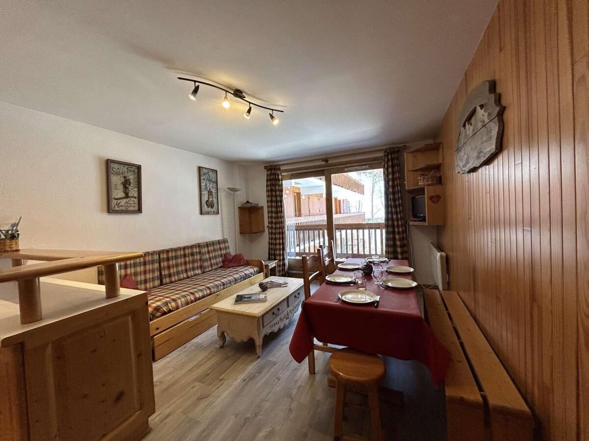 A cozy living room with a sofa, a dining table set for two, and a wooden bench.