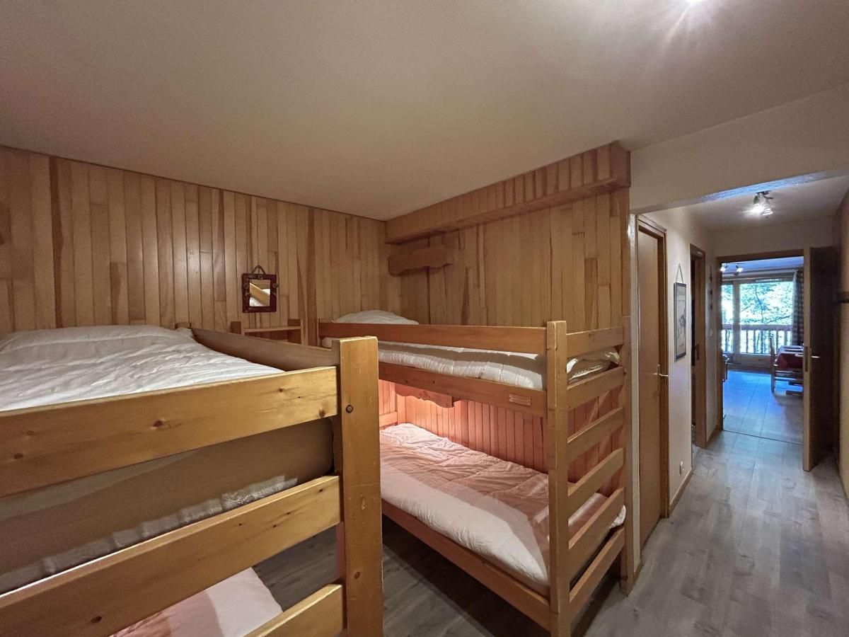A room with bunk beds, wooden walls, and a hallway leading to an outdoor area.