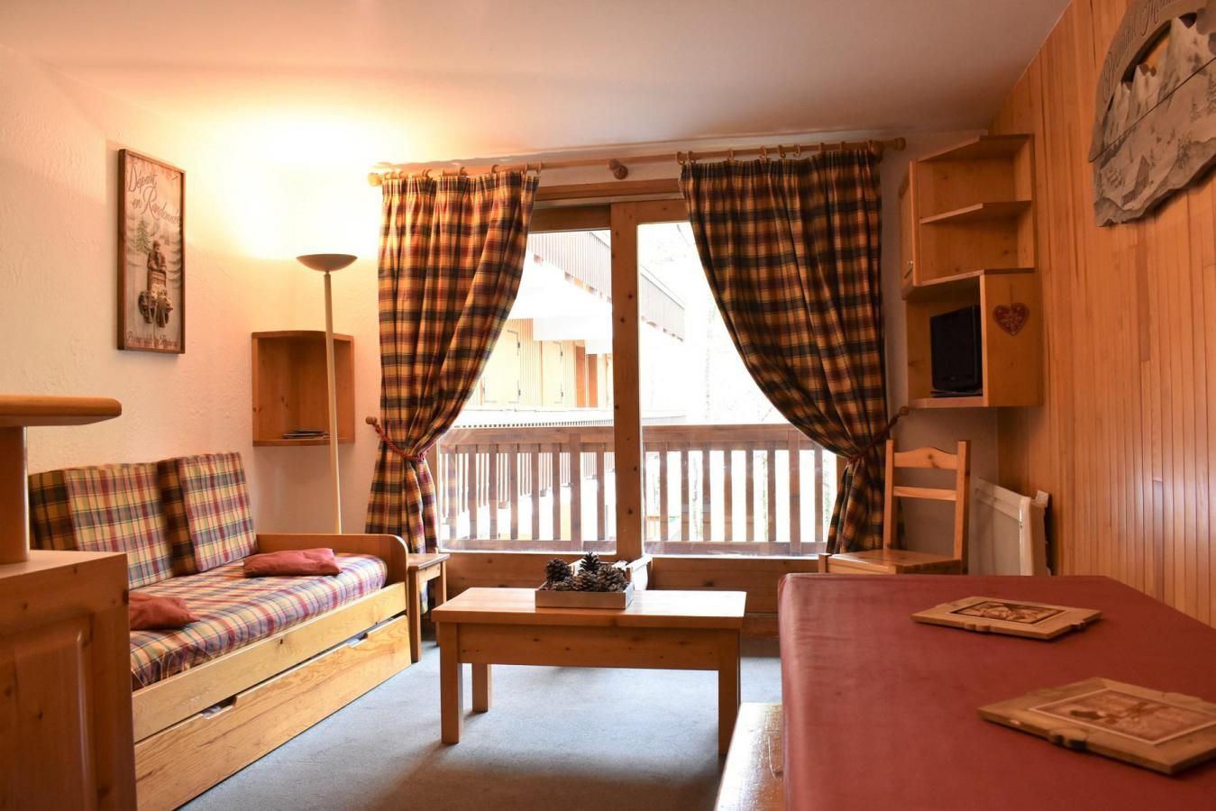 A cozy room with a bed, a sofa, a table, and a window with curtains.