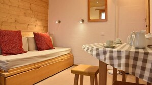 Una habitación acogedora con una cama, una mesa con mantel a cuadros y un espejo en la pared.