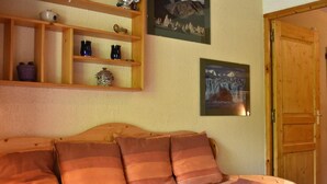 Une chambre confortable avec un lit en bois, une étagère ornée d’objets décoratifs et deux tableaux encadrés accrochés au mur.