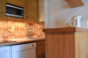 A kitchen with wooden cabinets, a microwave, a sink, and a dishwasher. - 150m from ski slopes, 3rd floor, balcony, tv, 24m², Méribel (Méribel - Les Allues)