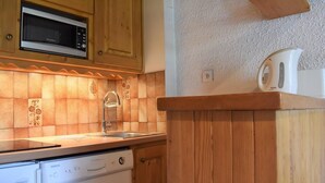 Une cuisine avec des meubles de rangement en bois, un four à micro-ondes, un évier et un lave-vaisselle.