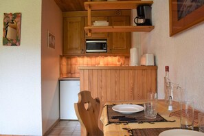 A compact kitchen with wooden cabinets, a microwave, and a coffee maker. - 20m from resort center, 3rd floor, balcony, tv, 24m², Méribel (Méribel - Les Allues)