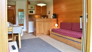 A compact living space with a kitchenette, a dining area, and a sofa. - 150m from resort center, 4th floor, balcony, ski locker, 26m², Méribel (Méribel - Les Allues)