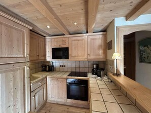 Une cuisine avec des meubles en bois, un four à micro-ondes, une cuisinière et une machine à café.
