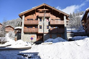 Un chalet à étages, construit en pierre et en bois, doté de balcons et offrant une vue sur un ciel dégagé.