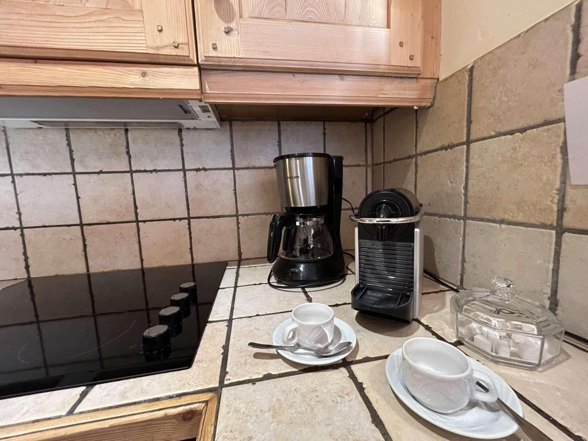 A kitchen with a black stovetop, a coffee maker, a microwave, and a glass container on the counter.