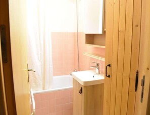 Een badkamer met een wit wastafel, een douche en een houten kastje.