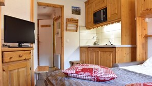 A compact room with a bed, a television, wooden cabinets, a microwave, and a small kitchenette. - 300m from shops, 2nd floor, balcony, tv, ski locker, 18m², Méribel (Méribel - Les Allues)