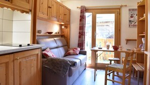 A compact kitchen with wooden cabinets, a built-in stove, and a dining area with a table and chairs. - 300m from shops, 2nd floor, balcony, tv, ski locker, 18m², Méribel (Méribel - Les Allues)