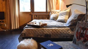 Un'accogliente camera da letto con un letto, un comodino con una lampada, un piccolo tappeto e una TV a muro.