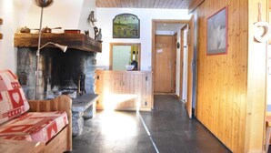 Una stanza accogliente con camino, pareti e soffitto in legno, e un corridoio che conduce ad altre stanze.