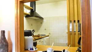 Una cucina con piano cottura, forno e cappa aspirante nera. Le pareti sono rivestite di piastrelle bianche e sono presenti mobili in legno.