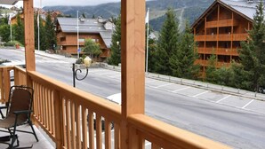 Un balcon en bois offrant une vue sur un paysage montagneux, une aire de stationnement et un immeuble doté de plusieurs balcons.