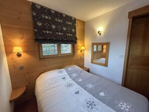 Ein gemütliches Schlafzimmer mit einem Bett, zwei Nachttischlampen, einem Fenster mit Ausblick und einem Spiegel an der Wand.