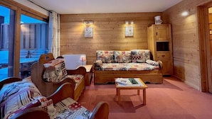 A cozy room with wooden walls, a sofa, a wooden cabinet, and a table. - 200m from ski slopes, 6th floor, swimming pool, tv, ski locker, 50m², Méribel (Méribel - Les Allues)